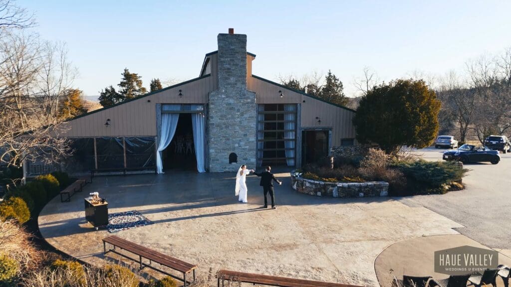 Bride and groom exiting Haue Valley wedding venue in Missouri with modern barn architecture and outdoor courtyard
