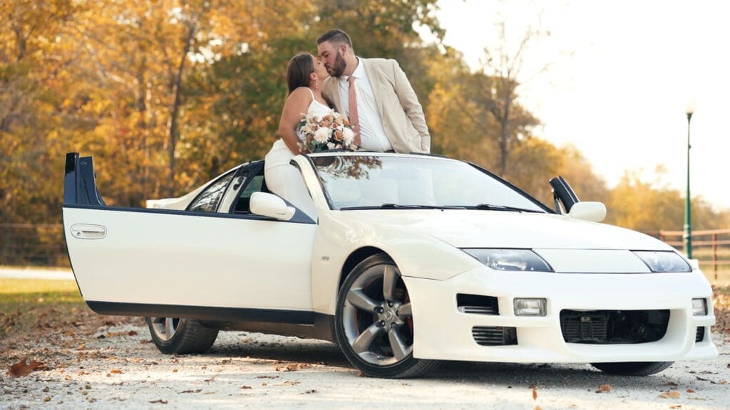 Bride and groom kissing beside a white sports car during their Red Oak Valley wedding
