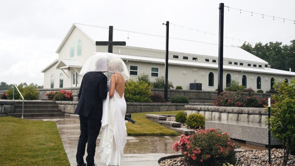 Bride and groom sharing an umbrella during a rainy wedding at Red Oak Valley's White Barn