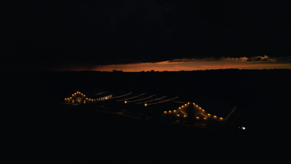 Aerial view of Red Oak Valley wedding venue and its illuminated barns at sunset